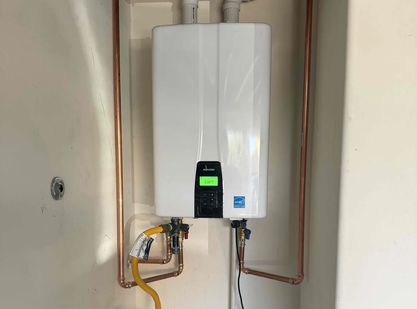 A wall-mounted Navien tankless water heater with copper pipework and gas connections