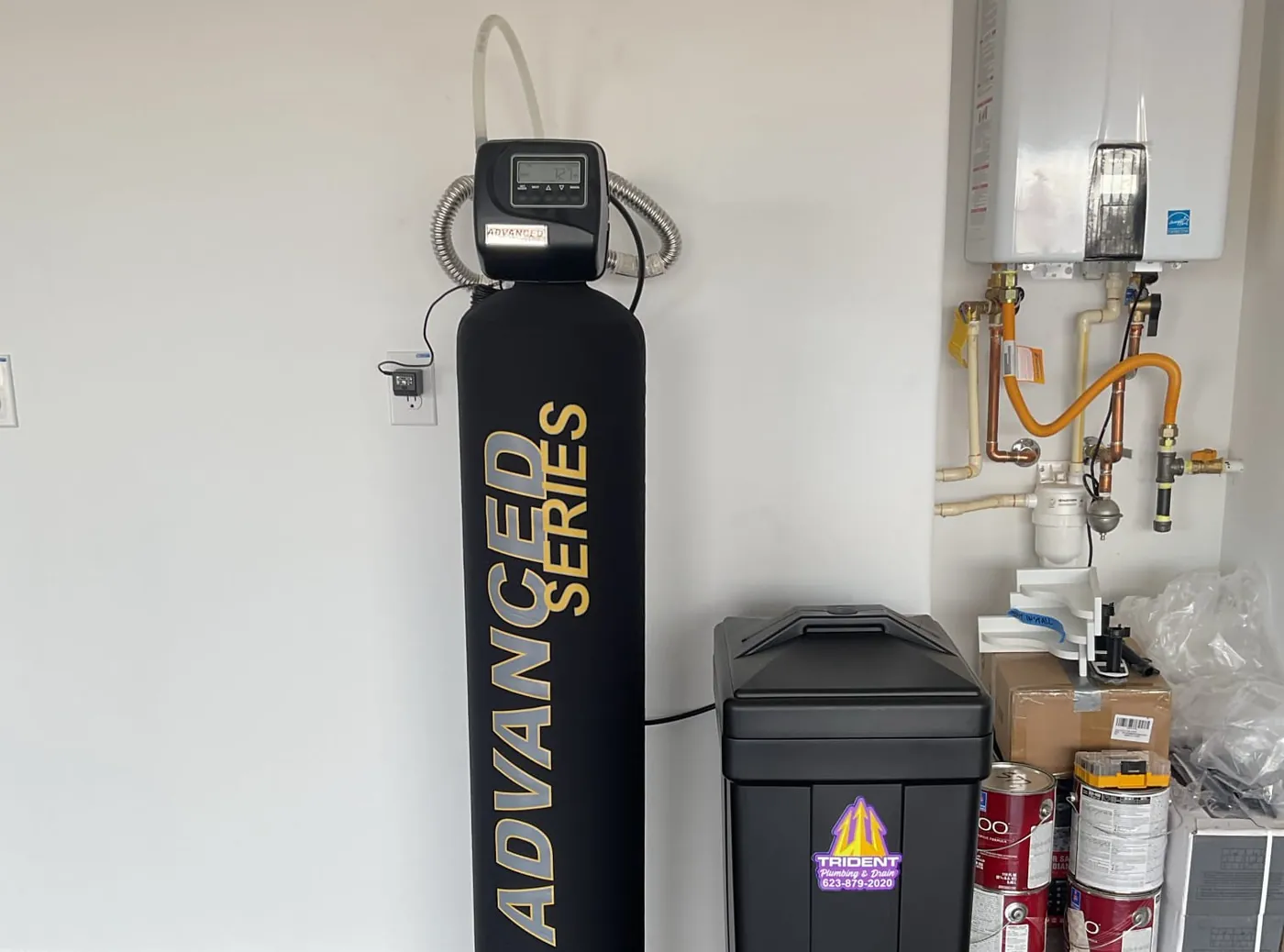 An Advanced Series water treatment tank and brine tank in a garage beside a wall-mounted tankless water heater