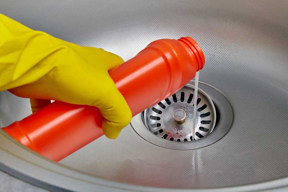 a frustrated person holding a bottle of drain cleaning solution